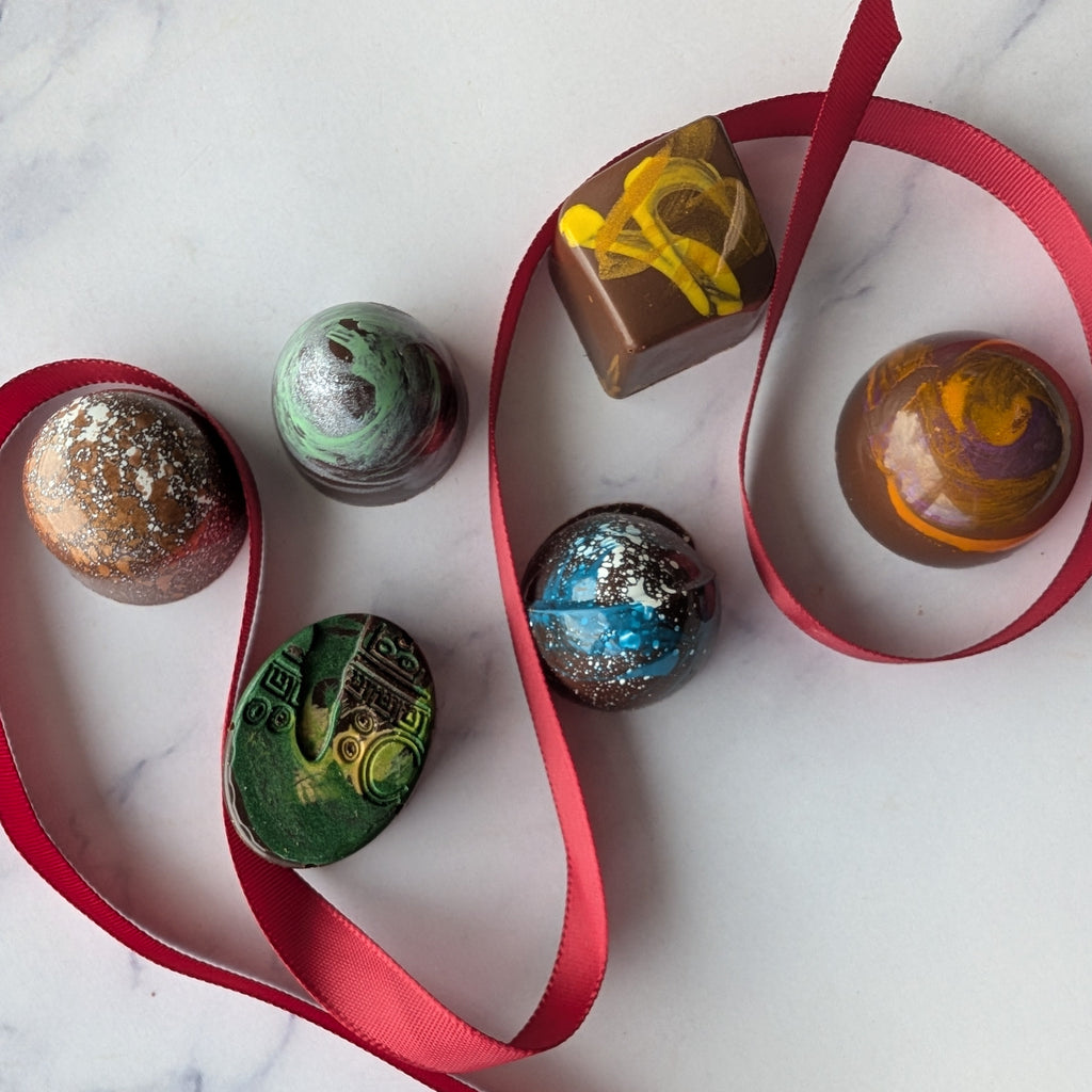 Colorful chocolate truffles on a white marble surface with red ribbon