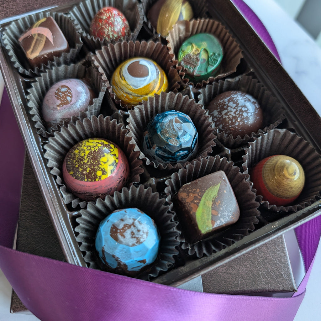 Assorted colorful chocolates in a box with a purple ribbon on a marble surface