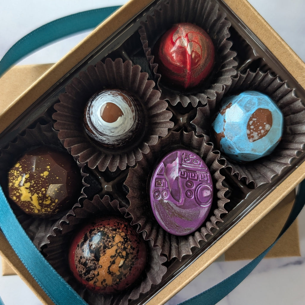 Box of chocolates with a blue ribbon on a marble surface.  hand painted chocolates