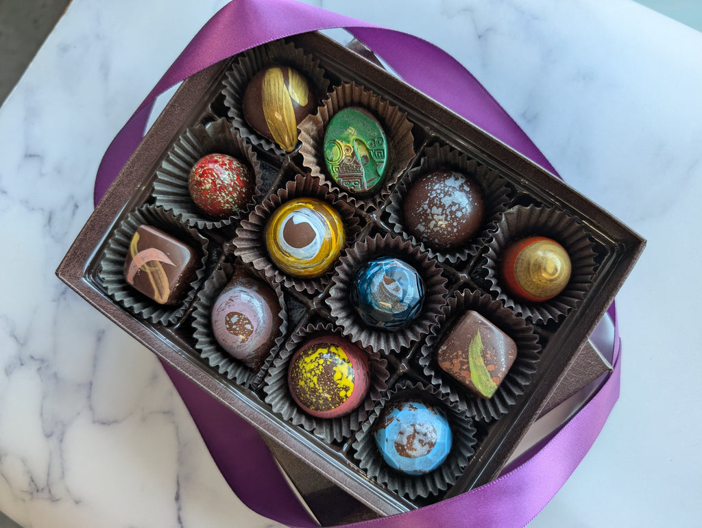 Box of assorted chocolates with a purple ribbon on a marble surface