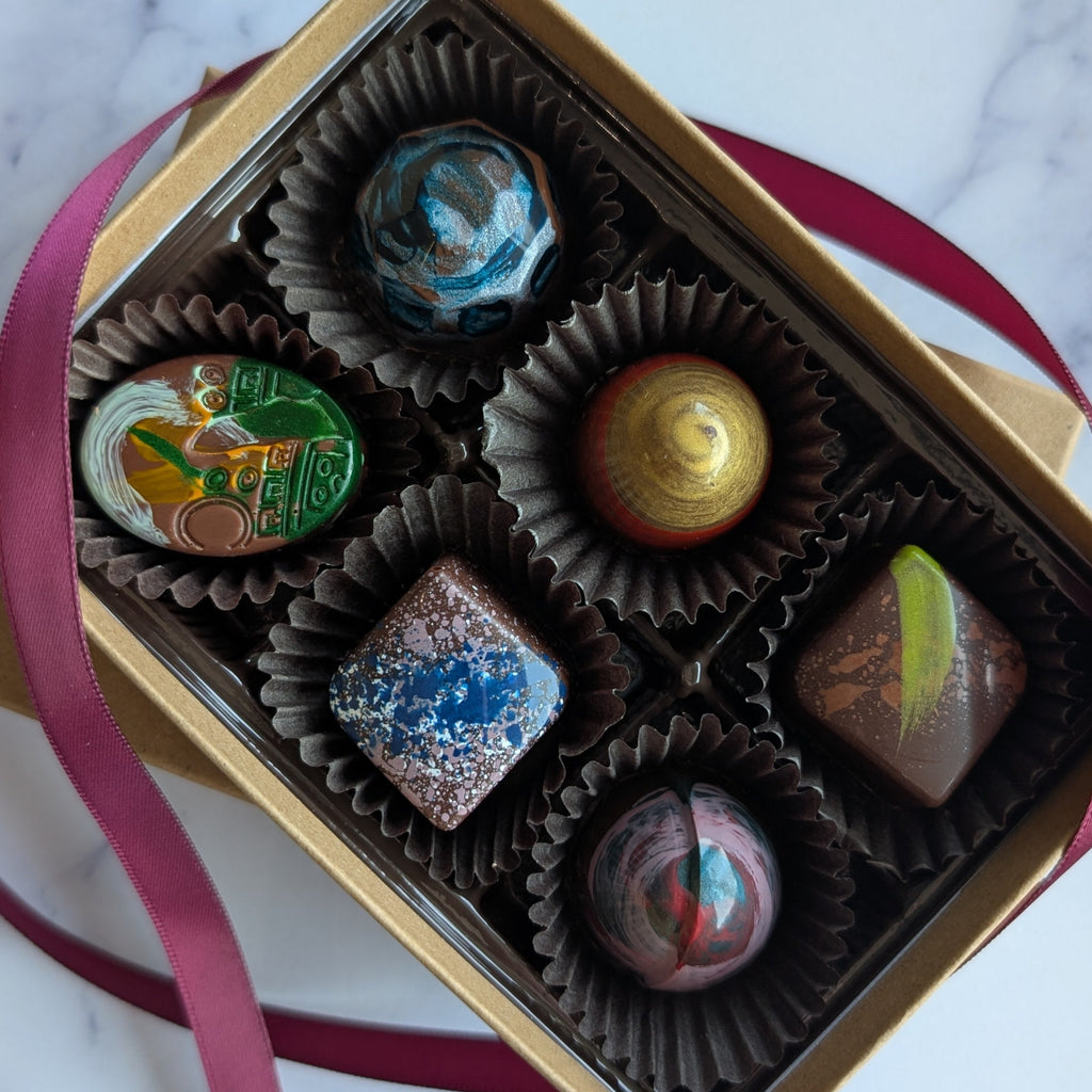 Box of chocolates with a pink ribbon on a marble surface.  hand painted truffles