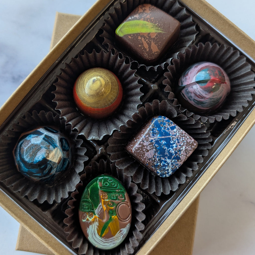 Box of assorted chocolates on a marble surface.  hand painted truffles