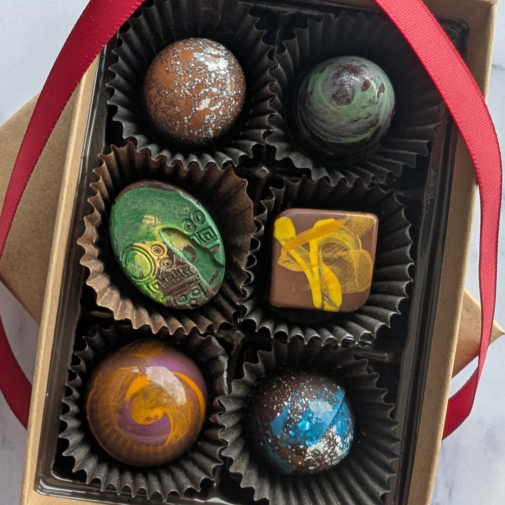 Box of chocolates with colorful toppings on a marble surface