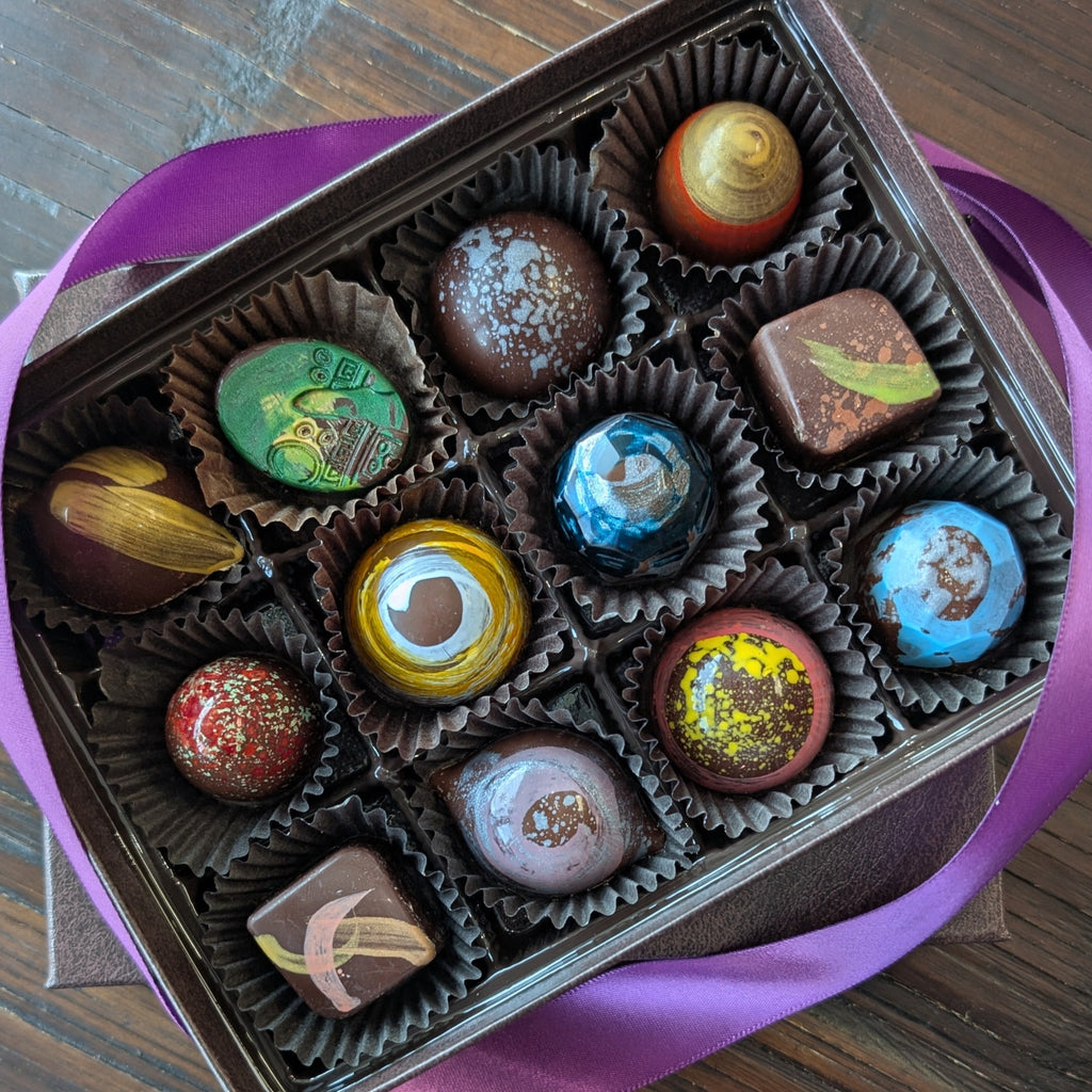 Box of chocolates with a pink ribbon on a wooden surface