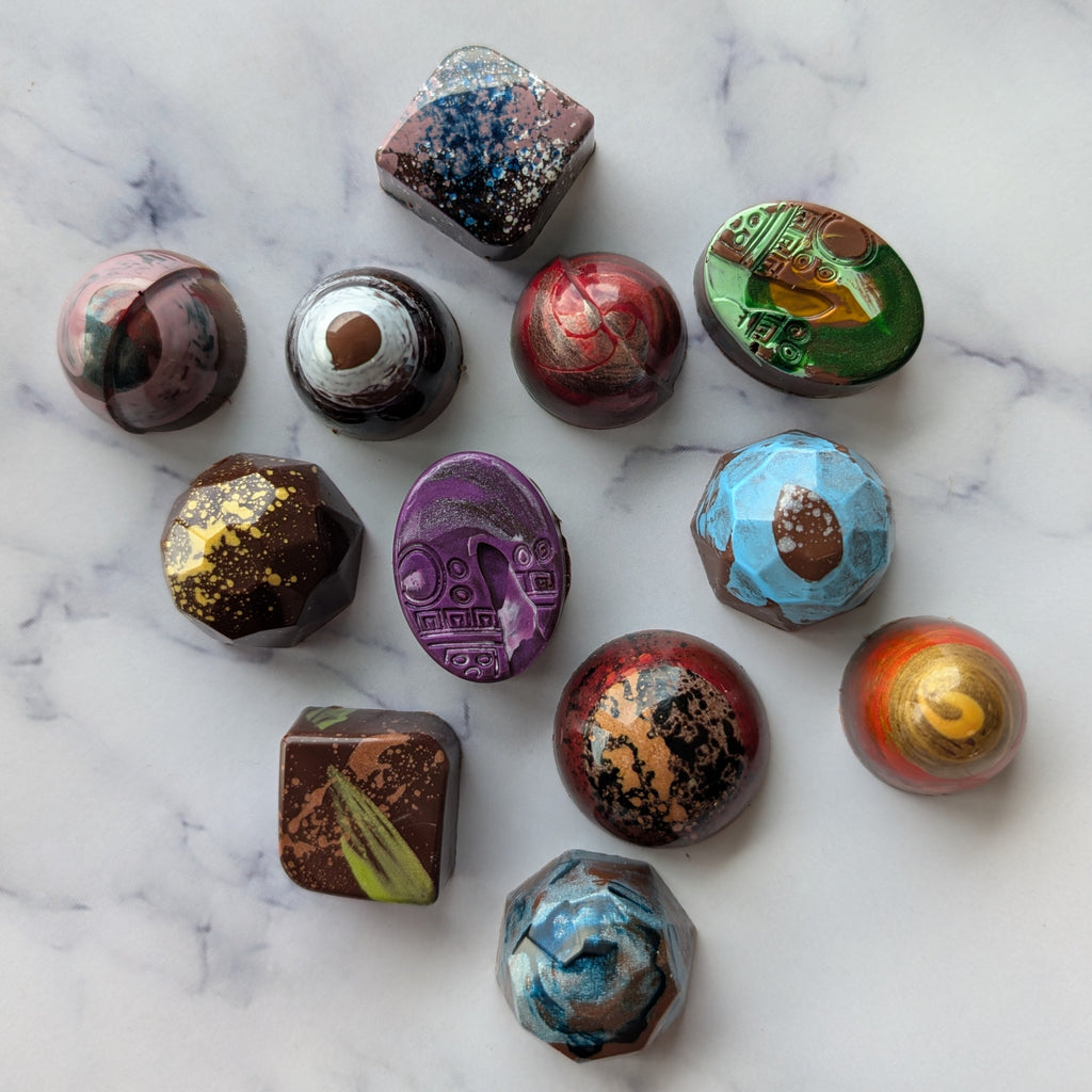 Assorted decorated chocolates on a marble surface.  signature hand painted truffles collection