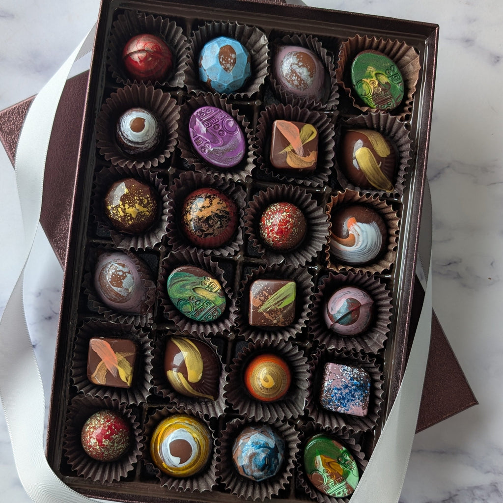 Box of assorted chocolates on a marble surface.  hand painted chocolates